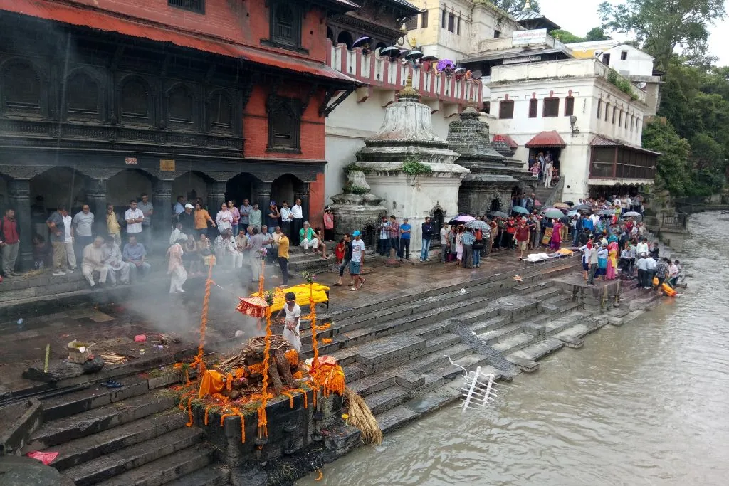 The Bagmati River at Pashupatinath, with the temple buildings, ghats, and small figures of people at dusk.