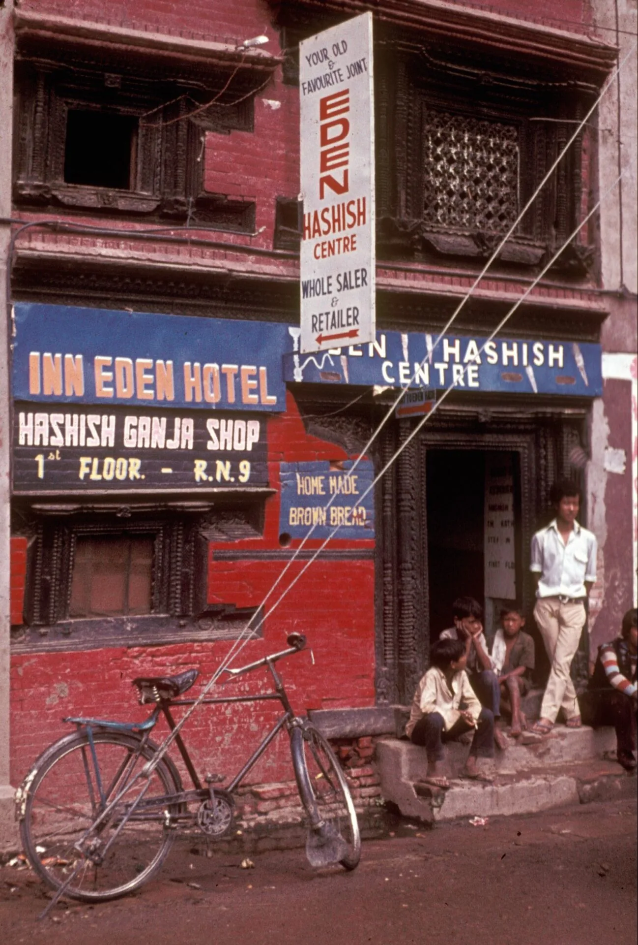 The Raju Hashish Centre and Inn Eden Hotel in Kathmandu, with hand-painted signs for hashish and ganja and a bicycle parked outside.